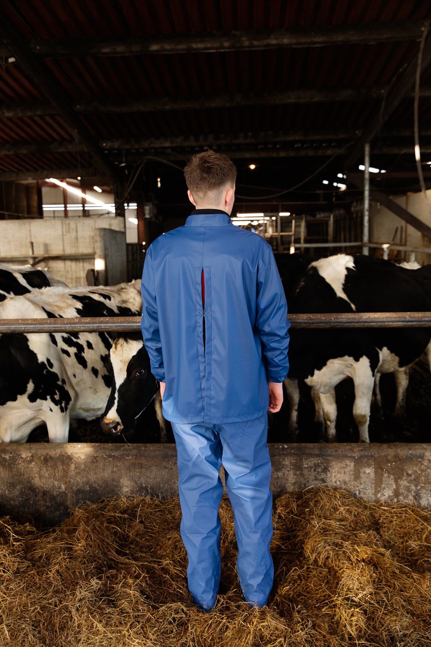 Man standing showing back of Wawets waterproof dairy top with velcro snap ties, breathable underarm, welded seams
